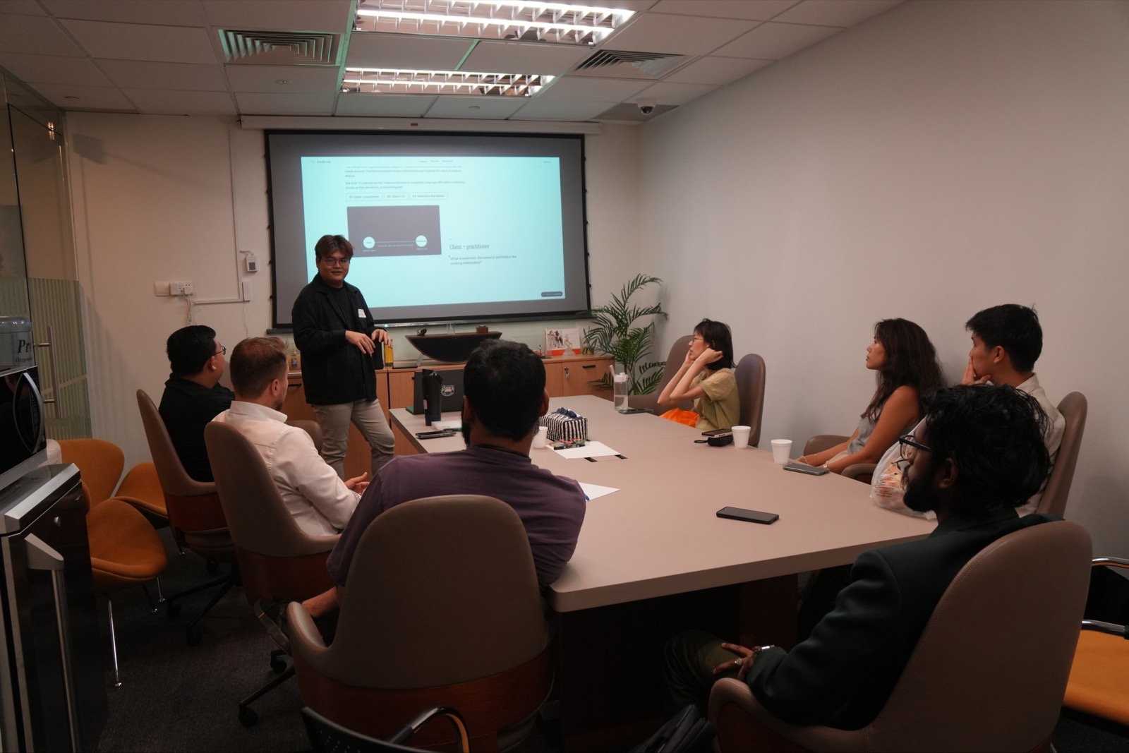 Facilitator presenting a slide on talking and listening to workshop participants seated around a conference table